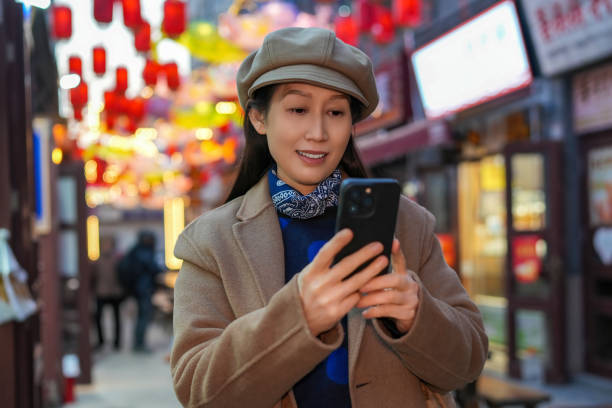 istock Modern Woman Engaging with Smartphone in Vibrant Market Setting 2194192999