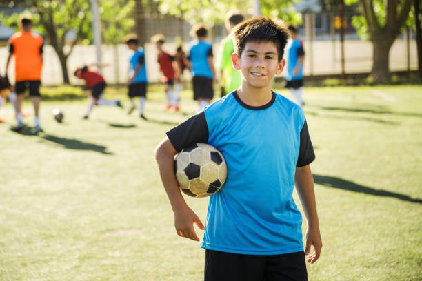 istock Young Boy Posing on Soccer Field with Teammates in Background 2194193266