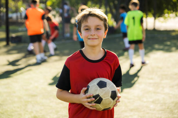 istock Young Boy Holding a Soccer Ball on a Sunny Field 2194193310