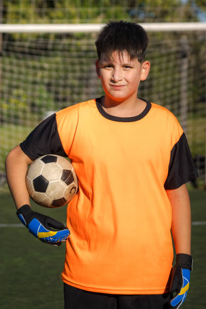 Midsection Of Man Holding Ball While Standing On Grass
