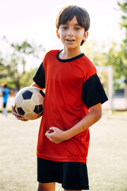 istock Young Boy Holding Soccer Ball in a Field During Sunset 2194193571