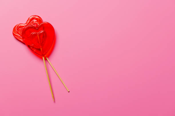 istock Heart-shaped lollipops arranged on a vibrant pink background 2194194944
