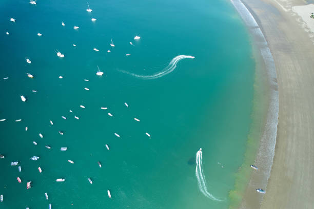 Boats making curly moves on blue water aerial above top drone view