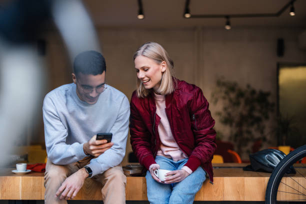 istock Friends Enjoying Coffee Together While Viewing Smartphone in a Cozy Cafe 2194195461