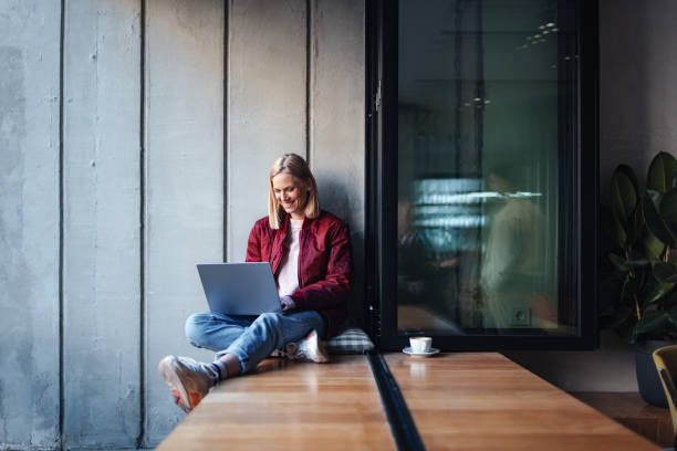 Young Woman Using Laptop at Cozy Cafe Window Seat