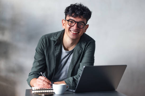 istock Young Professional Smiling While Working With Laptop and Notebook in a Cafe 2194195541