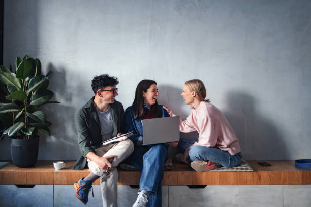 istock Group of Friends Laughing and Collaborating with a Laptop in a Cozy Setting 2194195561