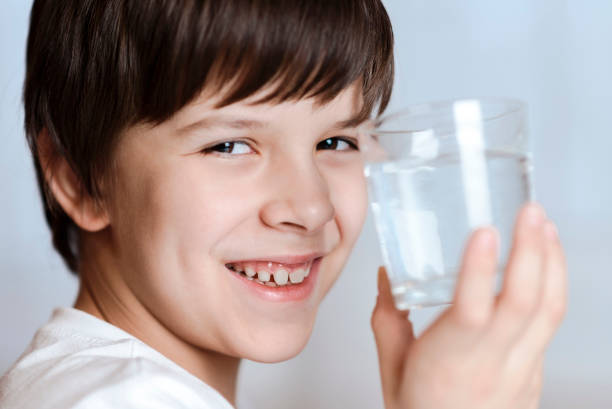 istock Cute child drinking water from a glass at home 2194195713