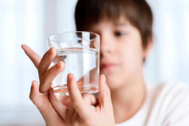 istock Cute child drinking water from a glass at home 2194195731