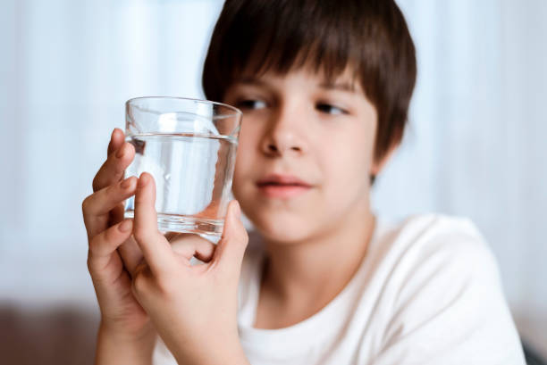 istock Cute boy drinking water from glass at home on white background 2194195980