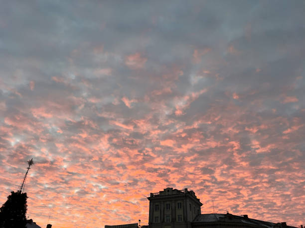 Buildings silhouetted against a dramatic sunset with vibrant orange clouds and a peaceful sky.