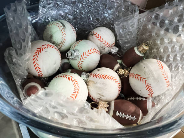 Assorted sports-themed ornaments in a container with cushioning material for protection