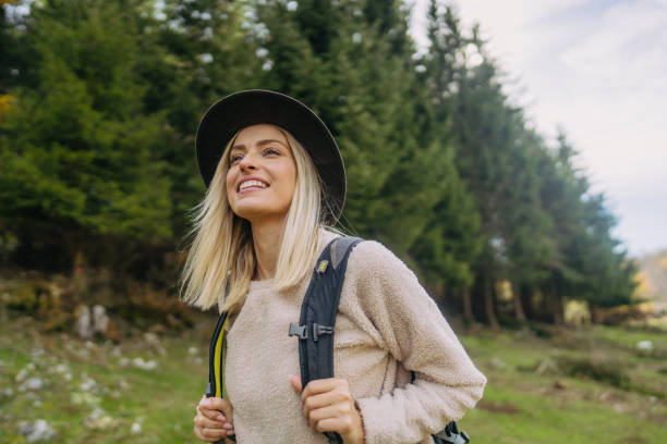 Photo of a young woman having a walk with a backpack through beautiful nature on a beautiful autumn day