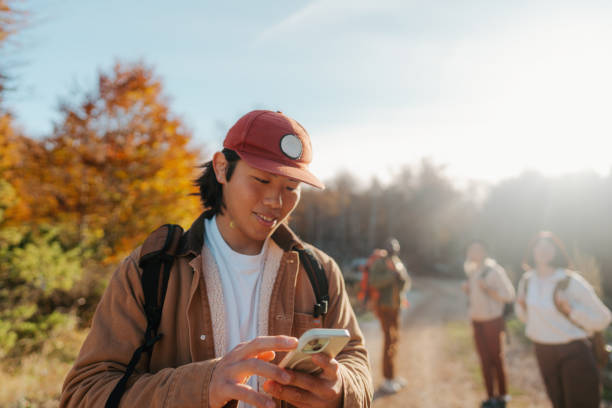 Young man using maps on mobile phone while on a hiking trip with friends