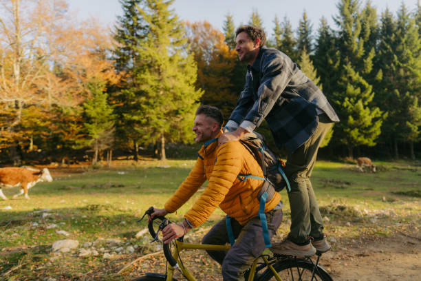 Photo of two mid adult man spending time together in nature on a beautiful and sunny autumn day, hiking and biking along the footpath