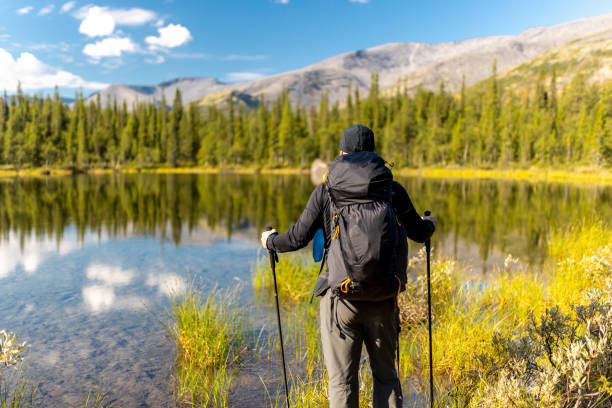 istock Hiker enjoying a reflective alpine lake in a serene forested mountain landscape 2194199125