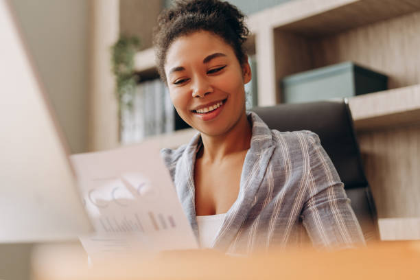 istock Smiling black businesswoman analyzing financial report in office 2194199224