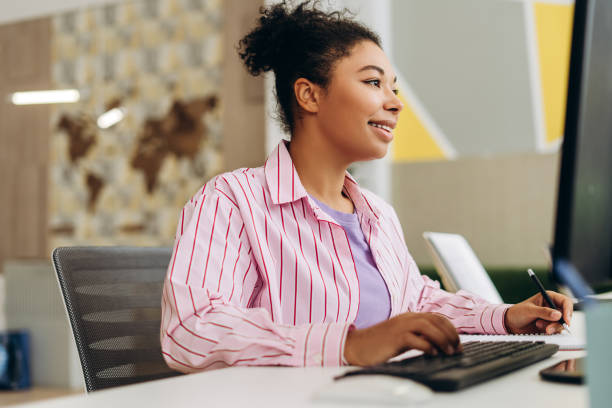 istock Smiling African American office manager working on computer and taking notes in modern office 2194199780