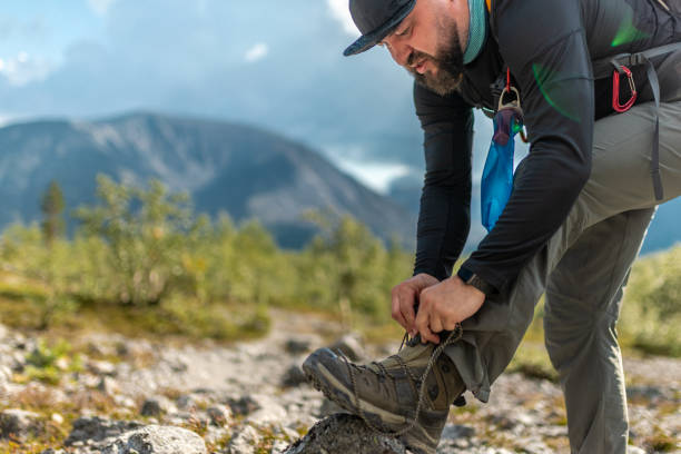 istock Man preparing for hiking adventure by tying boots in scenic mountain setting 2194199932