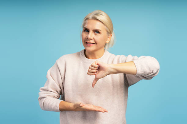 istock Woman showing thumbs down and open hand on blue background 2194201393