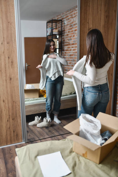 istock Joyful Female Looking at Herself in Mirror Trying on New Sweater She Ordered 2194201722