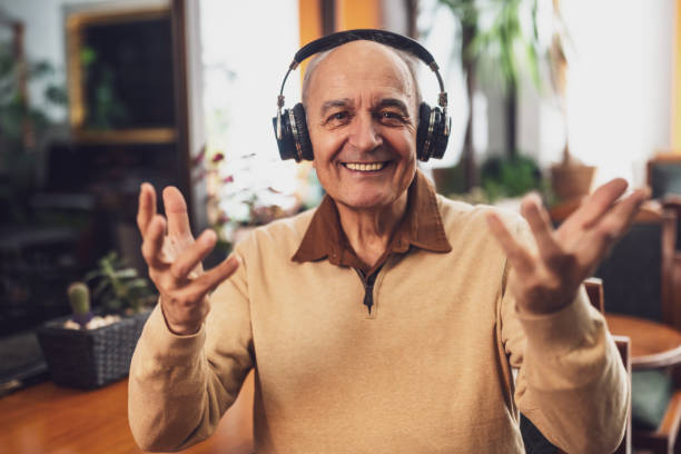 istock Happy senior man with headphones looking at camera and gesturing while having a video call 2194202229