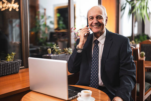 istock Older businessman using smart phone and laptop in the bar 2194202938