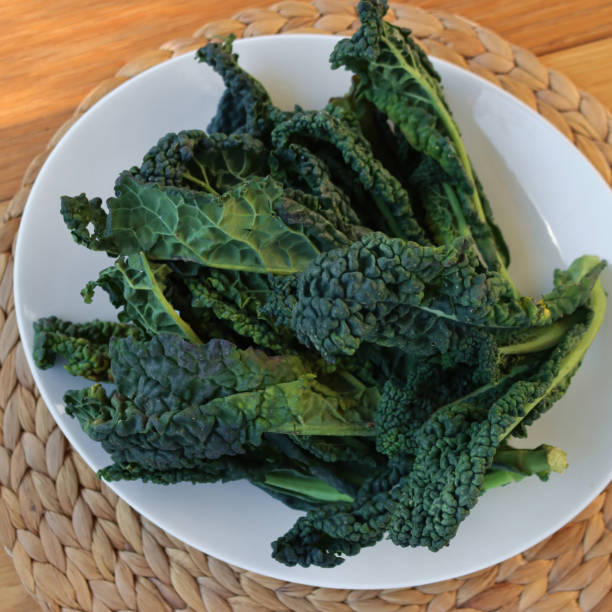 istock Fresh tuscan kale leaves on a white plate on wooden table 2194203130