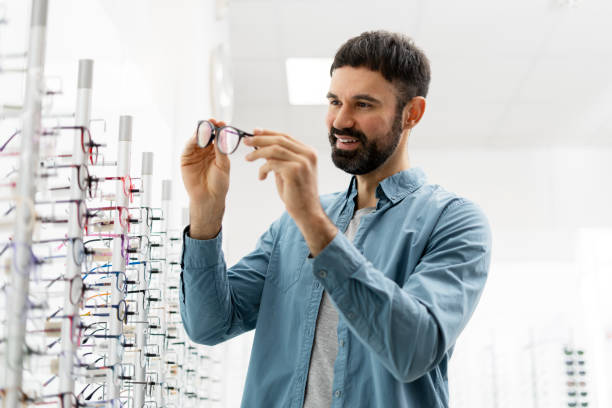 istock Smiling bearded man, customer choosing eyeglasses in optical store 2194207145