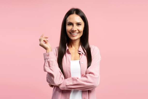 Smiling Latin woman gesturing with hand looking at camera on pink background. Advertisement concept