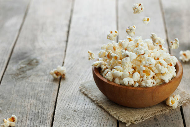 istock popcorn falling in wooden bowl on table 2194215341