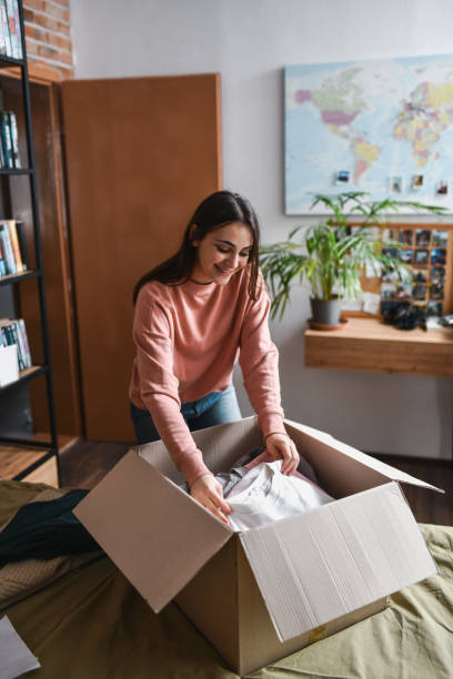 istock Excited Female Looking Down While Examining What's in Surprise Package She Received 2194216468