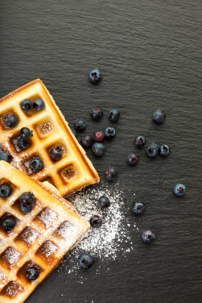 istock Waffles with blueberries and icing sugar on black slate background 2194218453