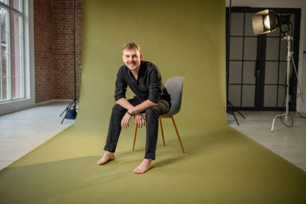 istock Barefoot man in black ensemble sitting and engaging. 2194219735