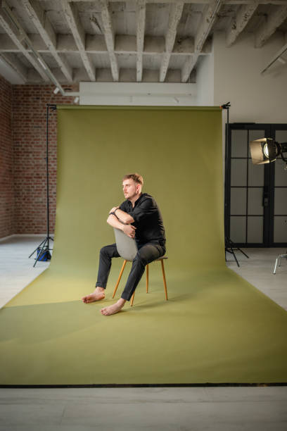 istock Barefoot man sits on chair on green studio floor 2194219909