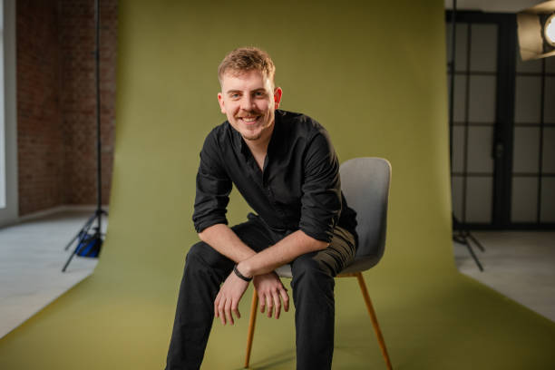 istock Casual seated man in black on green backdrop smiling. 2194221808