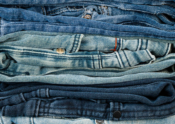 Different styles of denim jeans are neatly folded and organized by color