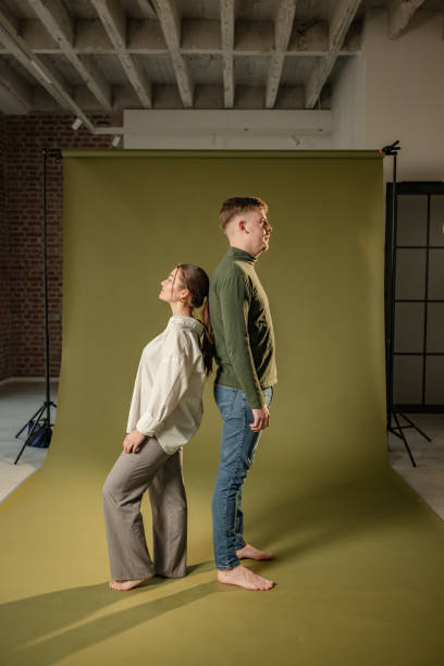 istock Couple back-to-back on olive green studio background. 2194222369