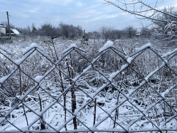 istock Snow-covered fence in the village under winter sunlight 2194222974