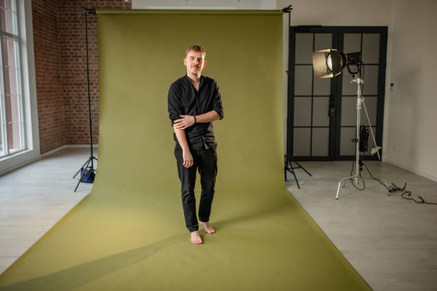 istock Man in black leaning forward on chair in studio. 2194224738