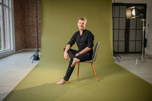 istock Man in black outfit posing on green background seated. 2194224758