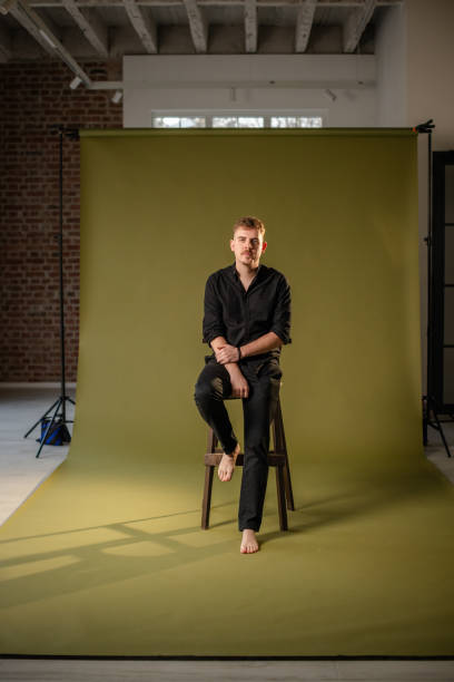 istock Man on stool against green background, focused look 2194224850