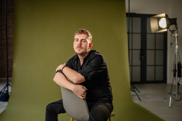 istock Man posing on chair in front of green backdrop 2194224952