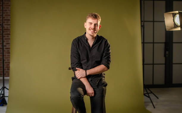 istock Man seated on stool in photography studio, smiling. 2194225044
