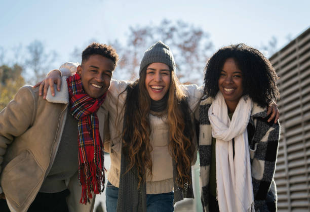 istock Three cheerful multi-ethnic students wearing winter clothes are embracing and smiling together outdoors 2194225528