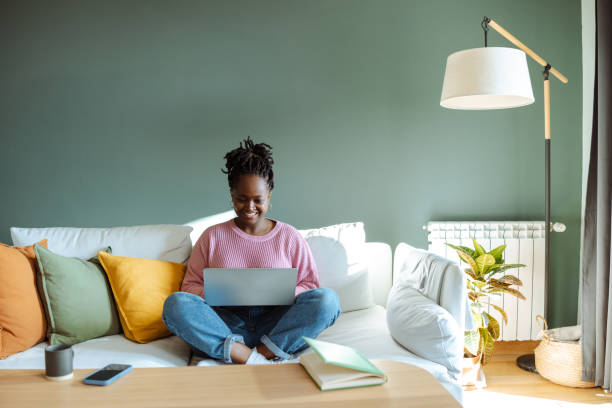 istock Young woman using a laptop while sitting on a cozy sofa at home 2194227505
