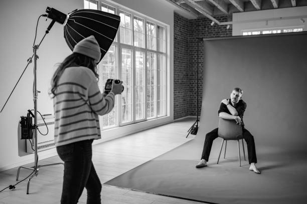 Photographer captures seated subject in studio setup.