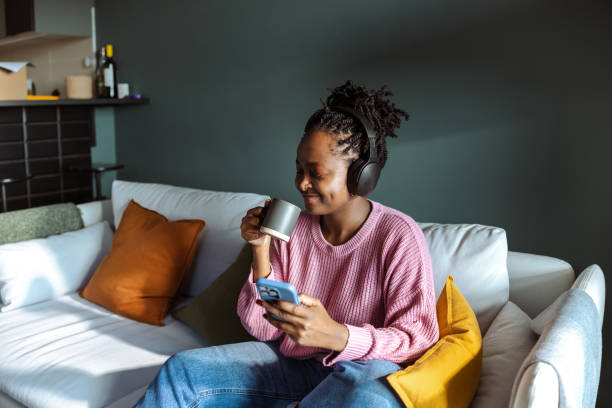 istock Smiling woman enjoying a coffee and using her smartphone on a cozy couch 2194227684