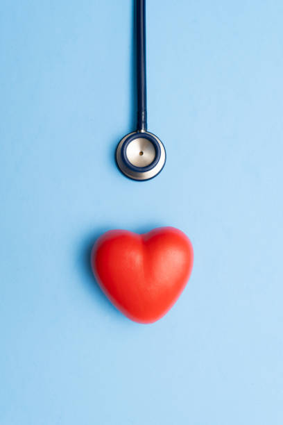 Medical stethoscope draped over bright red heart against deep blue backdrop, symbolizing cardiac health