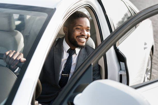 istock Man in Suit Smiling While Sitting in White Car With Door Open During Daytime 2194228921